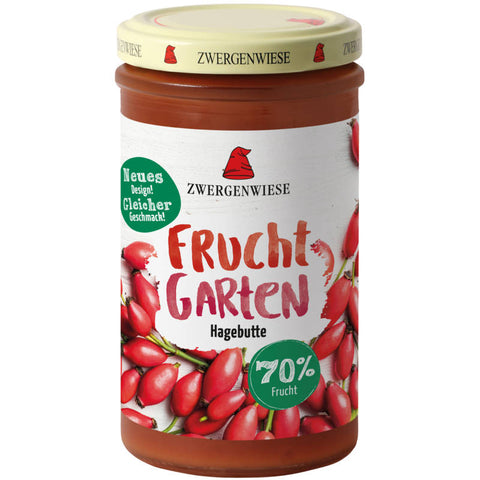 Frucht Garten Hagebutte - Glas mit Hagebuttenmarmelade, umgeben von frischen Hagebutten und grünen Blättern, auf einem rustikalen Holztisch arrangiert.