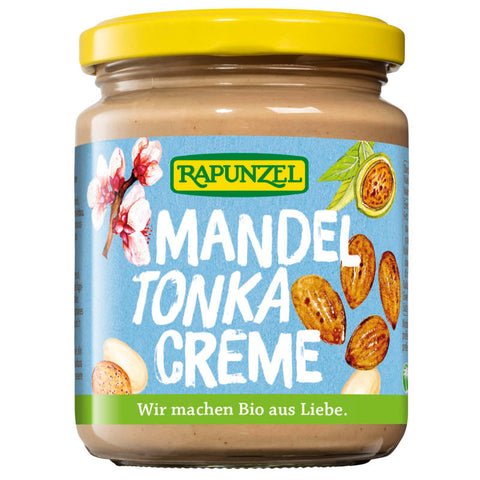 Glas mit Mandel-Tonka-Creme, einer cremigen Mischung aus Mandeln und Tonkabohnen, auf einem Holztisch mit Mandeln und Tonkabohnen im Hintergrund.