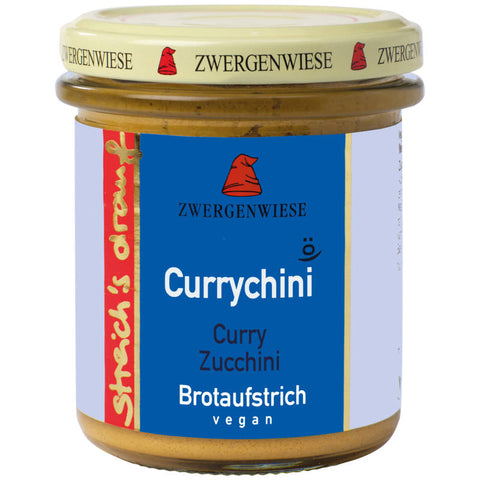 Glas mit Currychini-Aufstrich, einer würzigen Mischung aus Curry und Zucchini, auf einem Holztisch mit frischen Zutaten im Hintergrund.