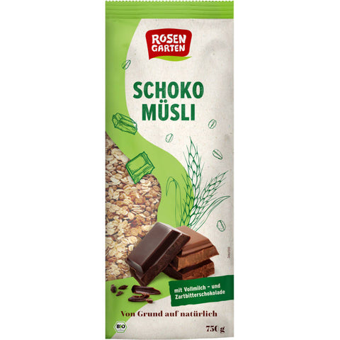 Eine Schüssel mit knusprigem Schoko-Müsli, gefüllt mit Haferflocken, Schokoladenstückchen und Nüssen, auf einem Holztisch mit einem Löffel daneben.