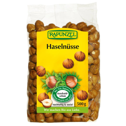 Eine Handvoll frischer, ungeschälter Haselnüsse auf einem rustikalen Holztisch, die die natürliche Qualität und den authentischen Geschmack des Haselnüsse Projekts repräsentieren.