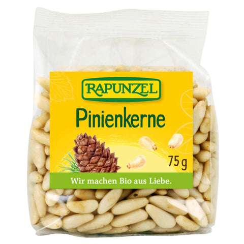 Eine Nahaufnahme von frischen, naturbelassenen Pinienkernen, die auf einer weißen Oberfläche liegen. Die Kerne sind länglich, cremefarben und haben eine glatte Textur.