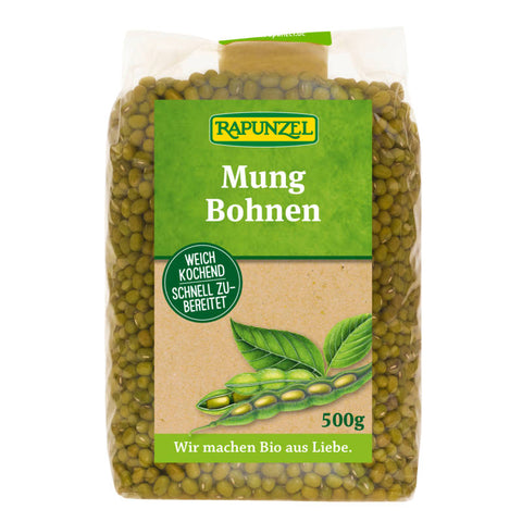 Eine Nahaufnahme von grünen Mungbohnen, die lose auf einer Oberfläche verteilt sind. Die Bohnen sind klein, rund und haben eine glatte, glänzende Oberfläche.