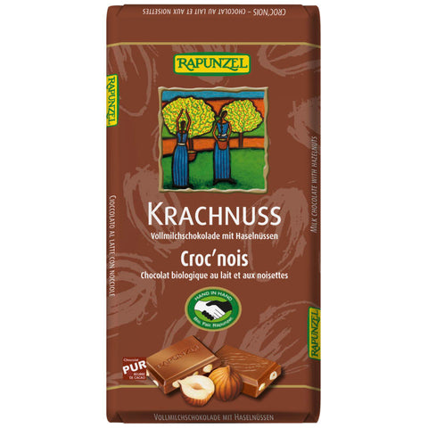 Eine Tafel Krachnuss Milchschokolade, verpackt in einer ansprechenden, farbenfrohen Verpackung mit Abbildungen von Nüssen und Schokoladenstücken.