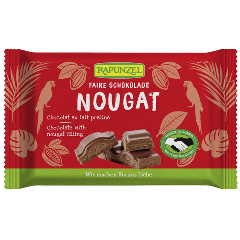 Eine Tafel cremige Nougat-Schokolade, verpackt in einer eleganten, goldfarbenen Folie. Die Schokolade hat eine glatte, glänzende Oberfläche und ist in gleichmäßige Stücke unterteilt, die zum Genießen einladen.