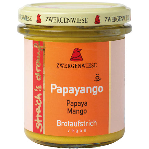 Brotaufstrich Papayango in einem Glasbehälter, umgeben von frischen Papayas und exotischen Früchten, auf einem rustikalen Holztisch arrangiert.