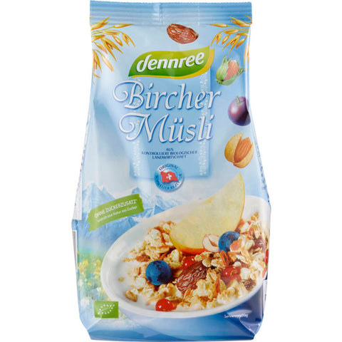 Schale mit Bircher Müsli, gefüllt mit Haferflocken, frischen Früchten und Nüssen, serviert auf einem rustikalen Holztisch.