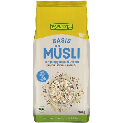 Schale mit Basis Müsli, bestehend aus Haferflocken, Nüssen und getrockneten Früchten, auf einem Holztisch mit frischen Beeren und einem Glas Milch im Hintergrund.