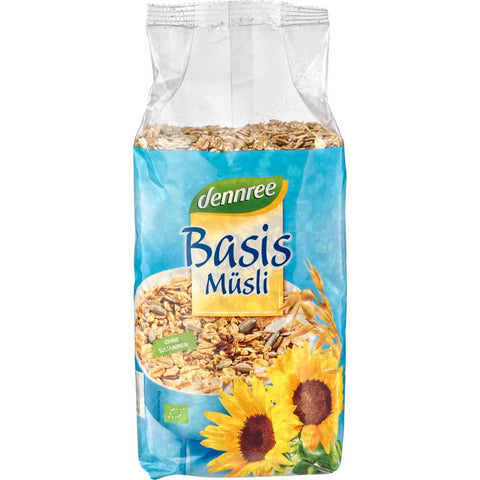 Schale mit Basis Müsli, bestehend aus Haferflocken, Nüssen und getrockneten Früchten, auf einem Holztisch mit frischen Beeren und einem Glas Milch im Hintergrund.