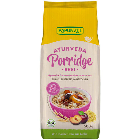 Eine Schüssel mit cremigem Ayurveda Porridge Brei, garniert mit frischen Beeren und Nüssen, auf einem rustikalen Holztisch.