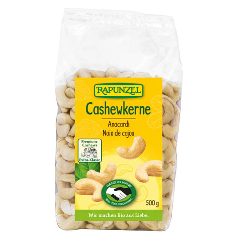 Eine Packung mit ganzen Cashewkernen, die in einer transparenten Tüte verpackt sind. Die Cashewkerne sind hellbeige und haben eine leicht gebogene Form. Im Hintergrund ist ein neutraler, heller Hintergrund zu sehen.