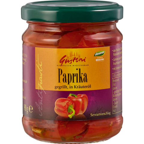 Gegrillte Paprika in aromatischem Kräuteröl, serviert in einem Glasbehälter. Die Paprikastreifen sind saftig und leicht angebräunt, durchzogen von frischen Kräutern und Gewürzen. Perfekt als Vorspeise oder Beilage.