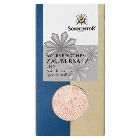 Ein Glasbehälter mit Ayurvedischem Zaubersalz, einer Mischung aus natürlichen Kräutern und Gewürzen, die traditionell in der ayurvedischen Heilkunst verwendet werden. Das Salz hat eine grobe Textur und eine warme, goldene Farbe.